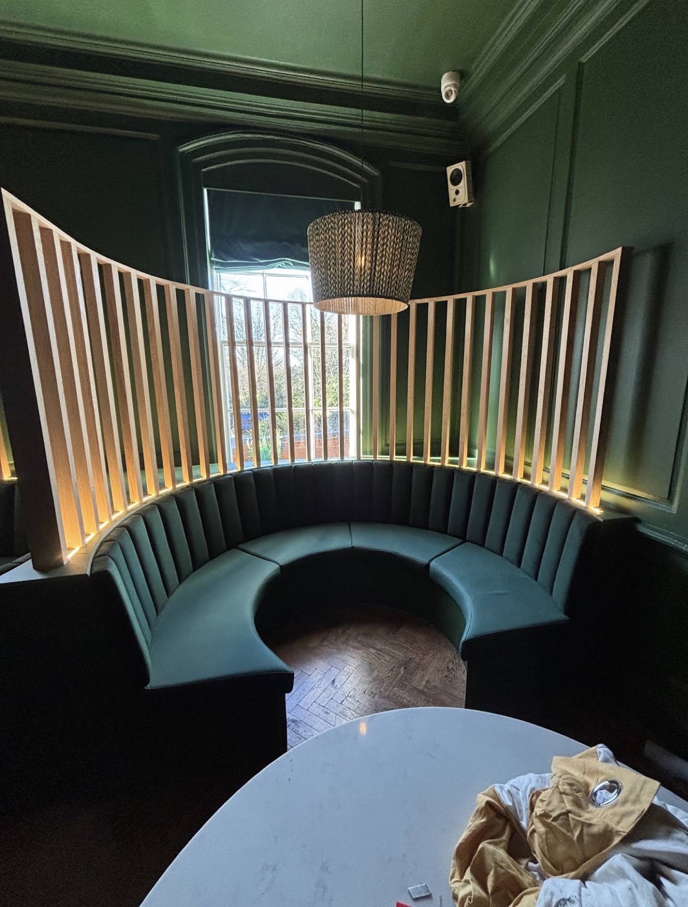 Custom curved banquette seating in forest-green interior, crafted by Thelwall