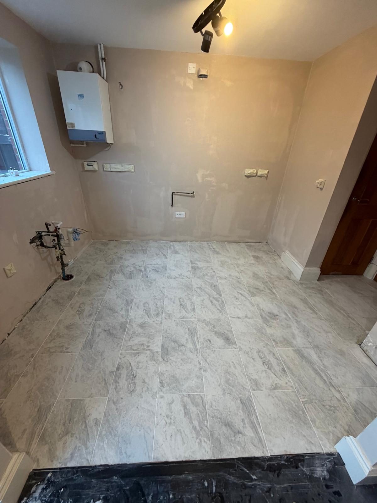 Same kitchen stripped back to plaster with a new floor laid and first-fix done